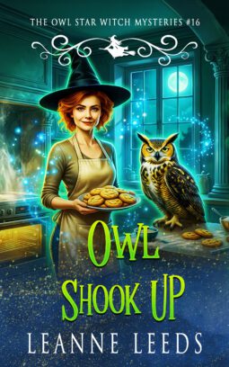 Book cover for Owl Shook Up by Leanne Leeds. Astra, a beautiful witch with a curly auburn bob wearing casual clothes and a baker's apron, stands in a magically lit kitchen holding a plate of snickerdoodle cookies. Her great horned owl companion, Archie, is perched attentively on the counter next to her.